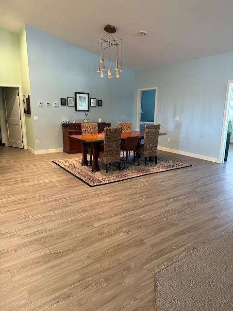 dining area with a notable chandelier, vaulted ceiling, and light hardwood / wood-style floors