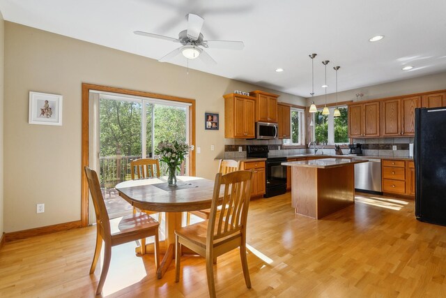 interior space featuring a wealth of natural light, black appliances, a center island, and hanging light fixtures