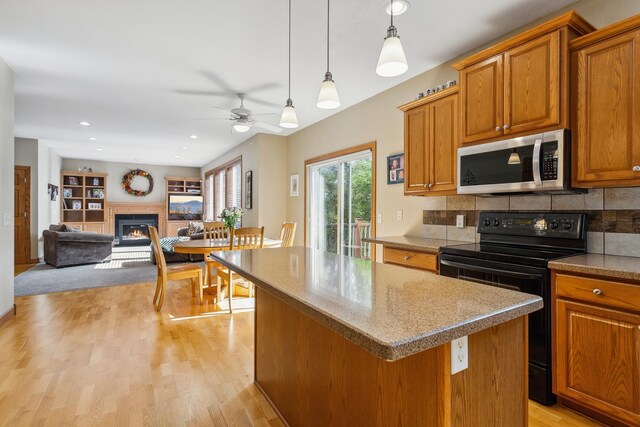 kitchen with ceiling fan, black electric range oven, tasteful backsplash, a center island, and light wood-type flooring