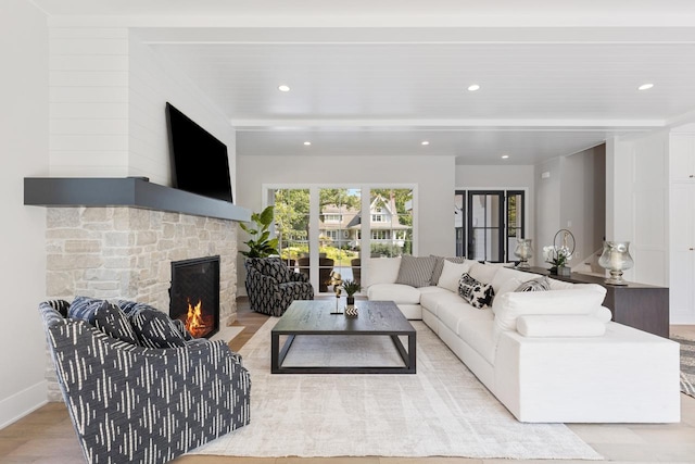 living room with light hardwood / wood-style floors and a stone fireplace