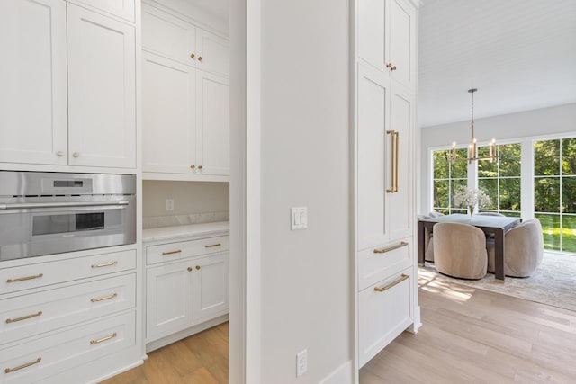 kitchen featuring decorative light fixtures, light wood-type flooring, plenty of natural light, and stainless steel oven