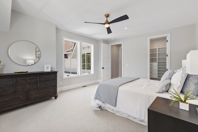 carpeted bedroom featuring a closet, ceiling fan, and a walk in closet