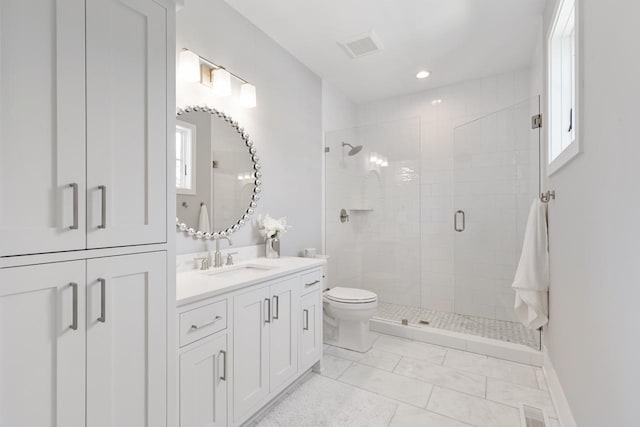 bathroom with vanity, a shower with shower door, toilet, and plenty of natural light