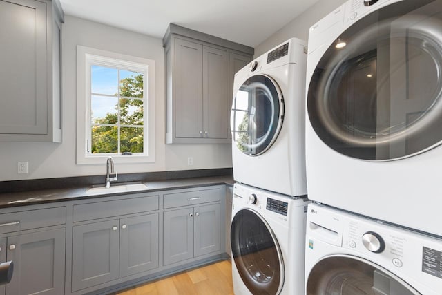 laundry room with sink, light hardwood / wood-style flooring, stacked washer / dryer, cabinets, and washer and dryer