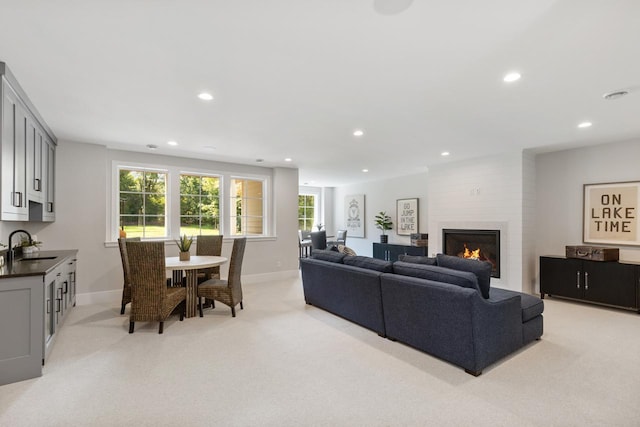 living room featuring light carpet, a fireplace, and sink