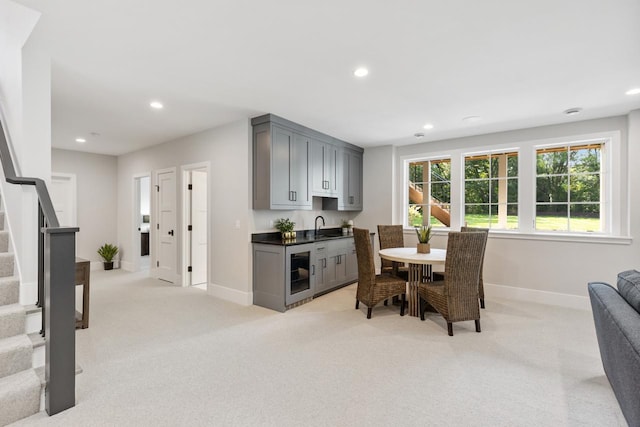 dining space featuring beverage cooler, light colored carpet, and sink