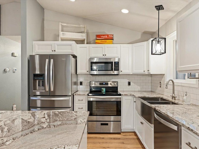 kitchen with appliances with stainless steel finishes, white cabinets, light wood-style flooring, and decorative backsplash