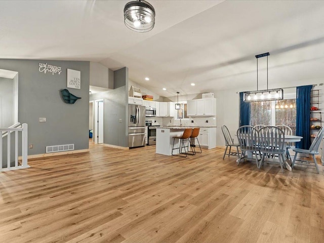 dining space with light wood finished floors, baseboards, visible vents, lofted ceiling, and recessed lighting