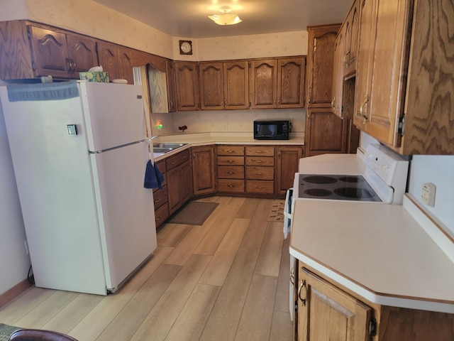 kitchen featuring light wood-type flooring, sink, and white appliances