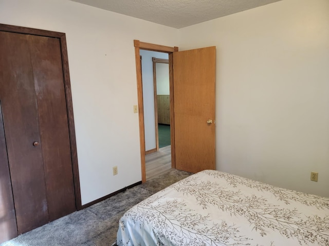 carpeted bedroom featuring a textured ceiling and a closet