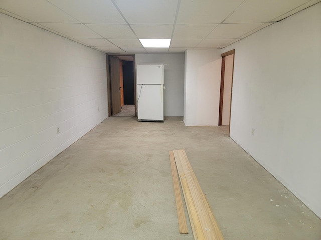 basement with a drop ceiling and white fridge