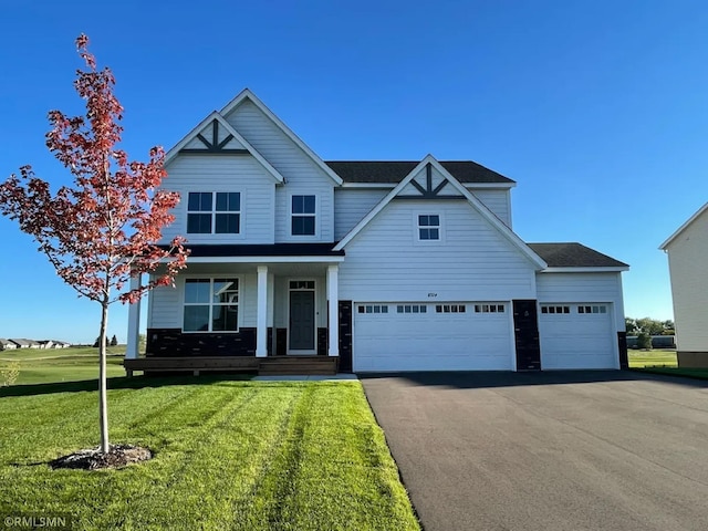 view of front of property with covered porch, a garage, and a front lawn