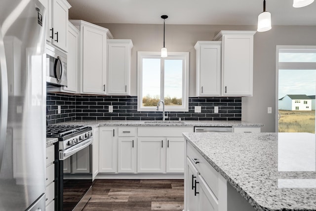 kitchen with appliances with stainless steel finishes, dark wood-type flooring, sink, pendant lighting, and white cabinets