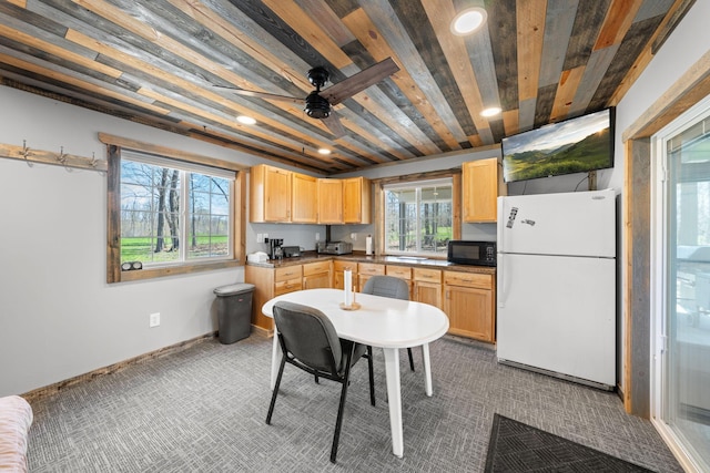 kitchen featuring freestanding refrigerator, black microwave, carpet floors, and plenty of natural light