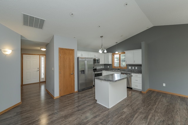 kitchen featuring pendant lighting, a center island, lofted ceiling, white cabinetry, and appliances with stainless steel finishes