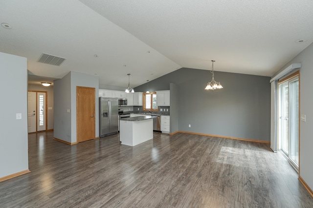 interior space featuring pendant lighting, a kitchen island, stainless steel appliances, and white cabinetry