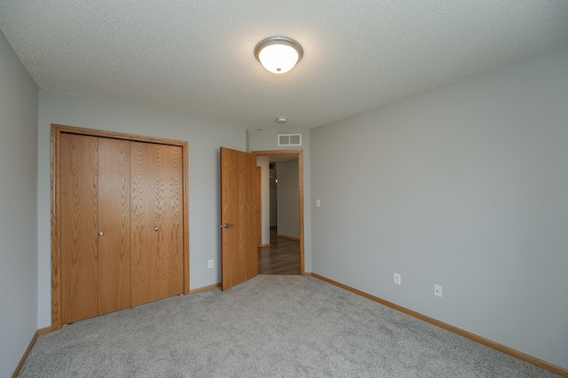 unfurnished bedroom with a closet, light colored carpet, and a textured ceiling