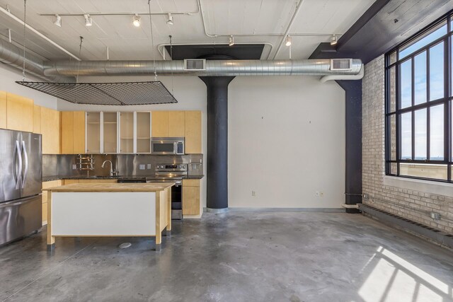 kitchen with a kitchen breakfast bar, stainless steel appliances, light brown cabinetry, and butcher block countertops