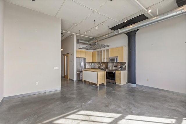 kitchen featuring tasteful backsplash, sink, a kitchen island, stainless steel appliances, and light brown cabinets