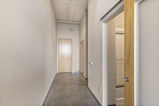 hall featuring a towering ceiling and concrete floors