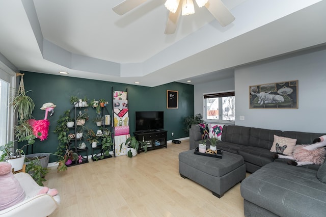 living room with a ceiling fan, a tray ceiling, wood finished floors, recessed lighting, and baseboards