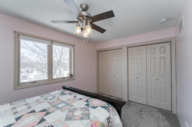 unfurnished bedroom with visible vents, two closets, carpet flooring, and a textured ceiling