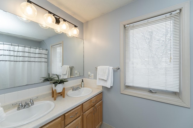 full bath with a sink, a shower with curtain, a textured ceiling, and double vanity