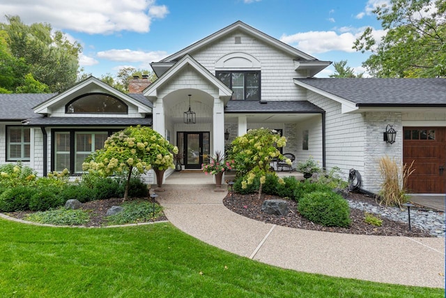 view of front of home featuring a front lawn, covered porch, and a garage