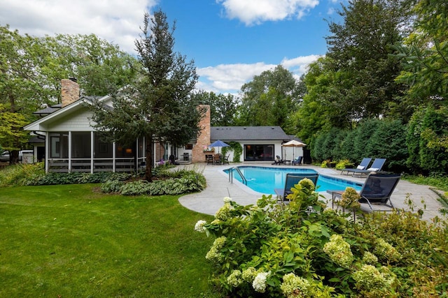 view of swimming pool featuring a sunroom, a lawn, and a patio area