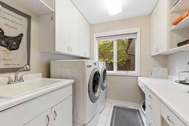 washroom with sink, light tile patterned floors, cabinets, and washer and dryer