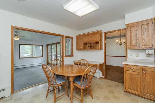 carpeted dining room with ceiling fan with notable chandelier and baseboard heating