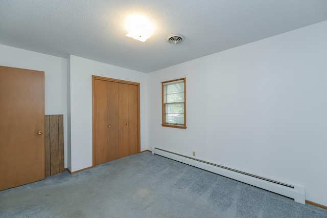 unfurnished bedroom with light colored carpet, a closet, baseboard heating, and a textured ceiling