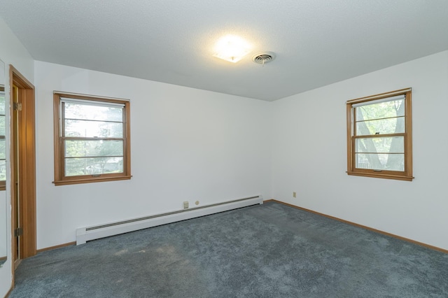 carpeted spare room featuring a baseboard heating unit, a textured ceiling, and plenty of natural light