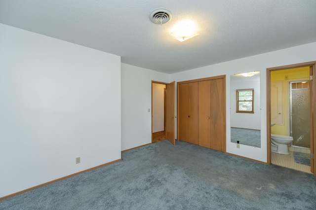 unfurnished bedroom with ensuite bathroom, a closet, carpet flooring, and a textured ceiling