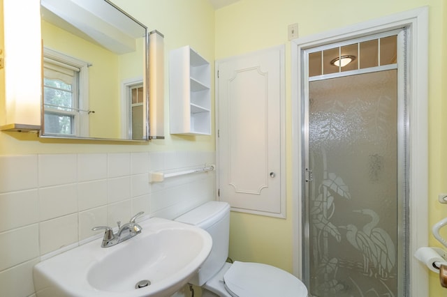 bathroom with sink, a shower with shower door, toilet, and tasteful backsplash