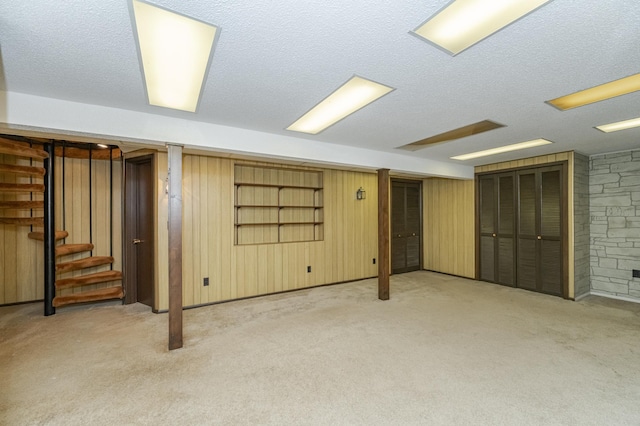 basement with light colored carpet, a textured ceiling, and wood walls