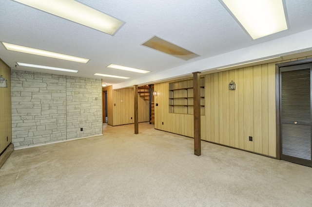 basement featuring a textured ceiling, wooden walls, and light carpet