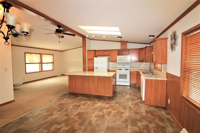 kitchen with vaulted ceiling with skylight, sink, ceiling fan with notable chandelier, wood walls, and white appliances