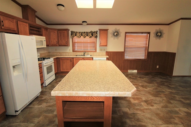 kitchen with wood walls, sink, white appliances, and a kitchen island