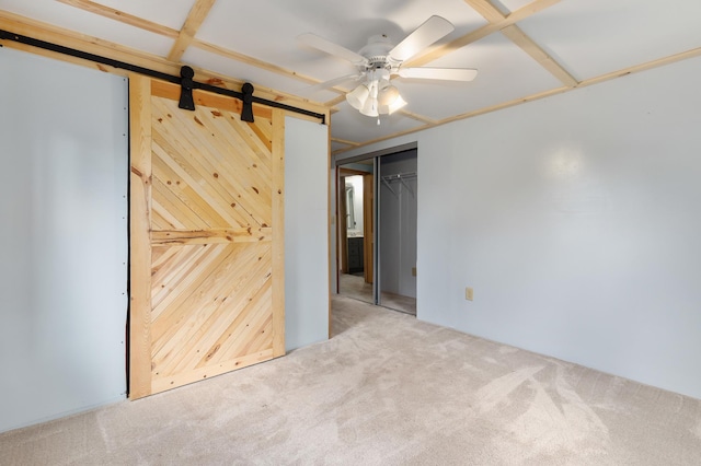 2135 24th Ave SW, Pine River Twp, MN 56474 - unfurnished bedroom featuring a barn door, carpet floors, wooden walls, a closet, and ceiling fan