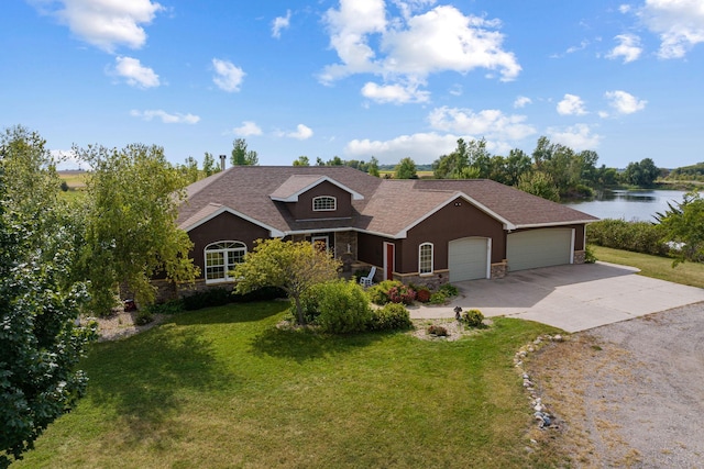 view of front facade with driveway, stone siding, an attached garage, a water view, and a front yard