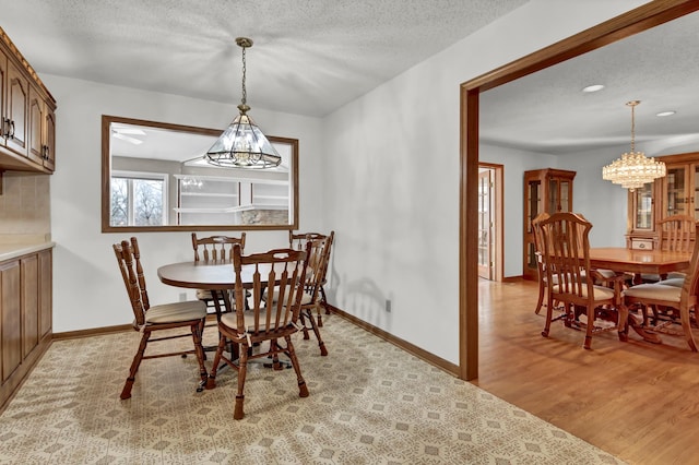 dining space with a chandelier, light hardwood / wood-style floors, and a textured ceiling