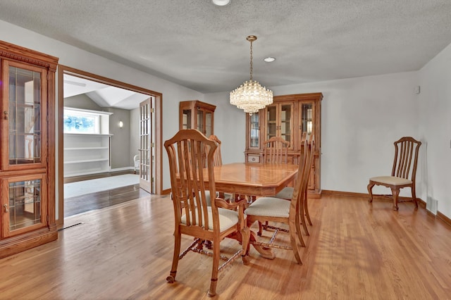 dining room with an inviting chandelier, a textured ceiling, and light wood-type flooring