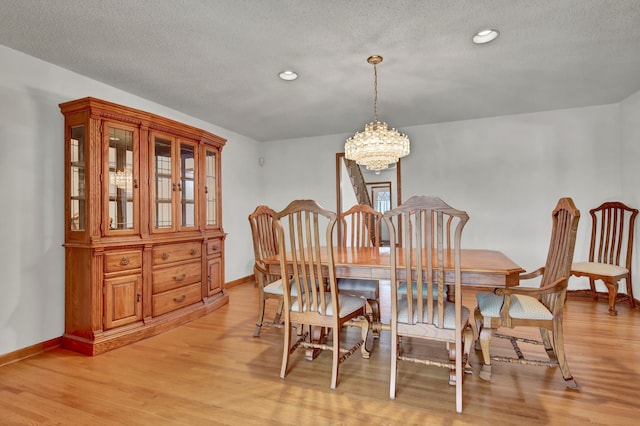 dining room featuring an inviting chandelier, light hardwood / wood-style flooring, and a textured ceiling