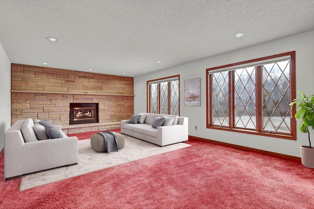 carpeted living room featuring a stone fireplace and a textured ceiling