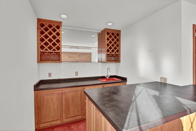 kitchen featuring sink, a textured ceiling, and kitchen peninsula