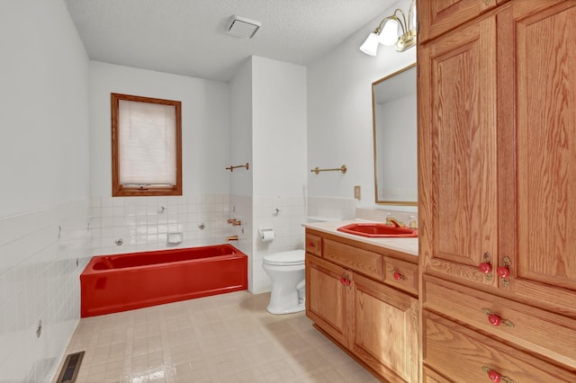 bathroom featuring tile walls, vanity, toilet, and a textured ceiling