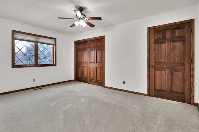 unfurnished bedroom with ceiling fan, light colored carpet, and a textured ceiling