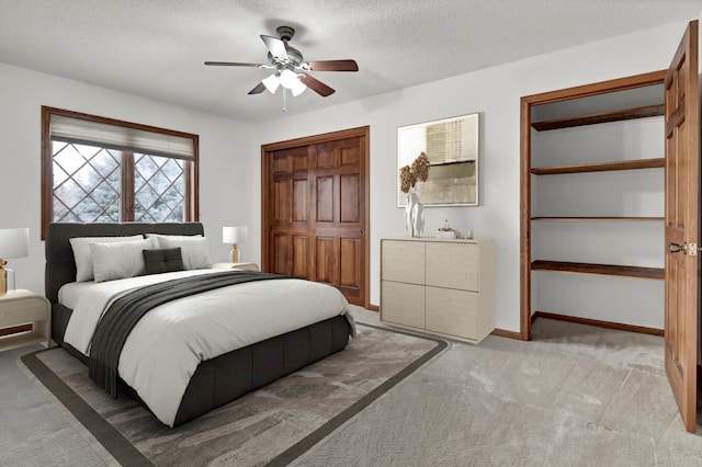 bedroom with ceiling fan, light colored carpet, a textured ceiling, and a closet