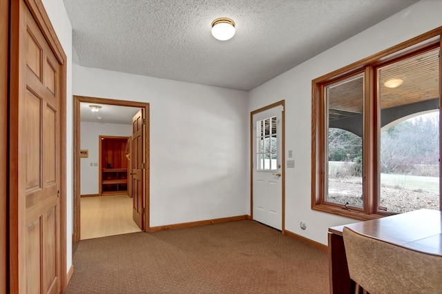 foyer with light colored carpet and a textured ceiling